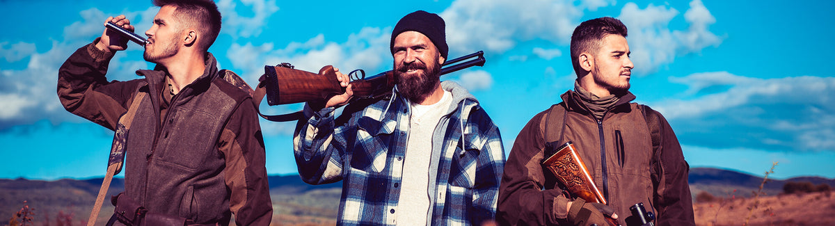 Three hunters in field jackets with rifles over their shoulders